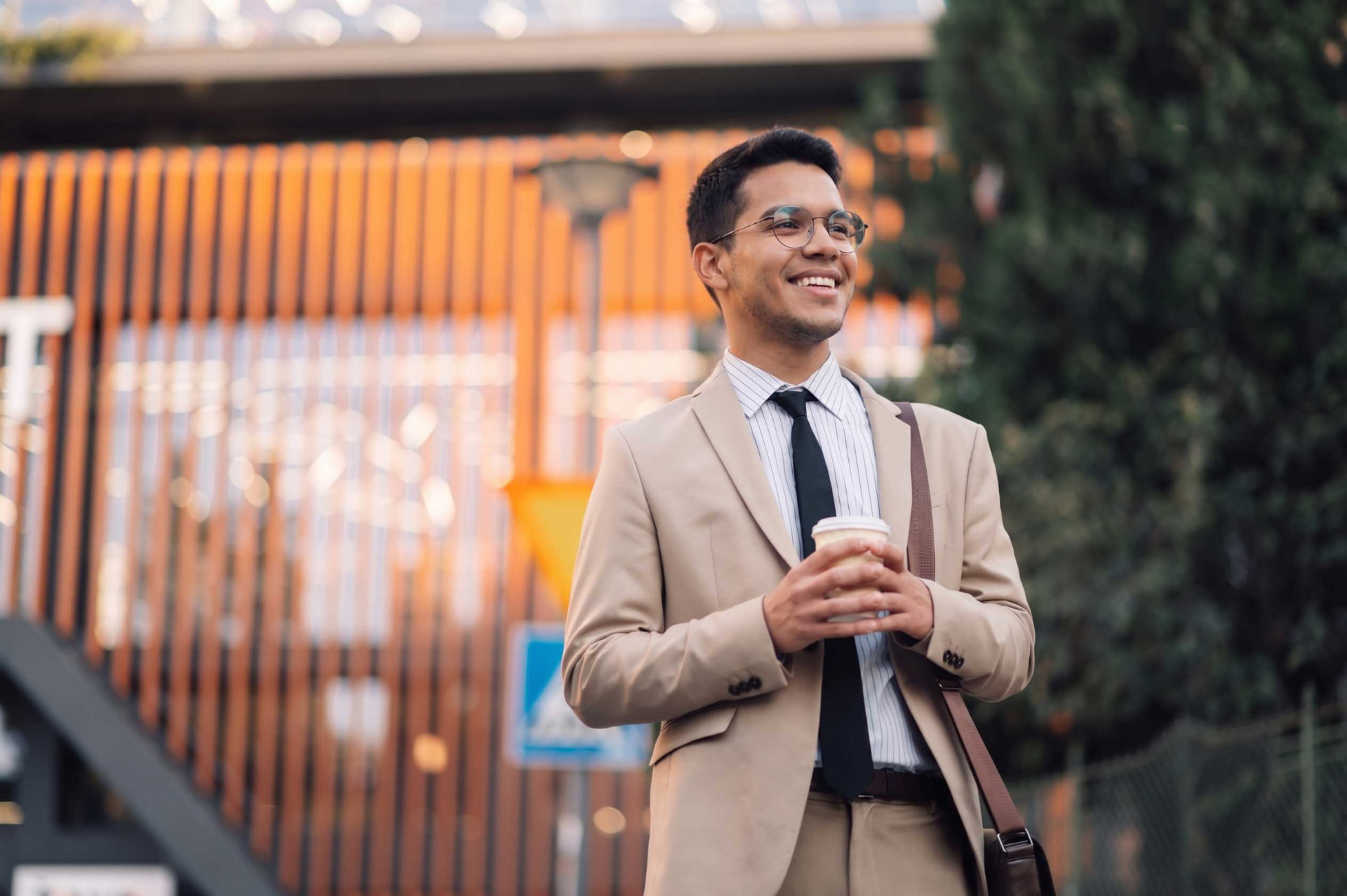 Joven profesionista con café en mano sonriendo con confianza